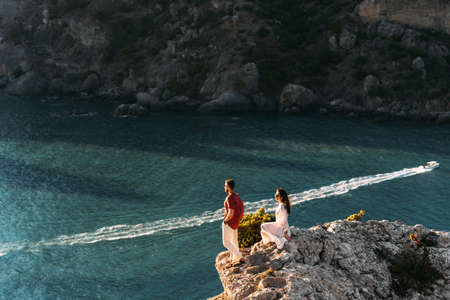 Couple in love at dawn by the sea. Honeymoon trip. Man and woman meet the sunset by the sea. Man and woman traveling. Wedding travel. Holiday romance. Beautiful couple by the sea. Copy spaceの写真素材