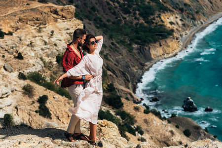 Beautiful couple hugging by the sea. Honeymoon trip. A man and a beautiful woman by the sea. A couple in love is traveling. Vacation by the sea. Couple on a seascape background. Copy spaceの写真素材