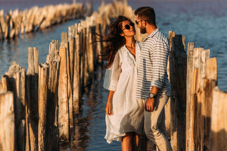 Young romantic couple hugging and about to kiss in beautiful sunset. Portrait of a couple in love at sunset by the sea. Beautiful couple in love enjoying their honeymoon. Copy spaceの写真素材