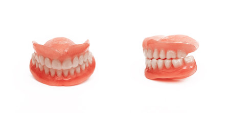 Full removable plastic denture of the jaws. Set of dentures on a white background. A side view of a dental prosthesis, isolate. Two acrylic dentures. Dentures or false teeth, close-up. Copy spaceの写真素材