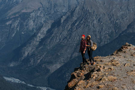 A couple in love on a rock admires the beautiful views. A man and a woman on a rock. A couple in love travels. A man and a woman in the Caucasus mountains. Couple traveling through the mountainsの写真素材