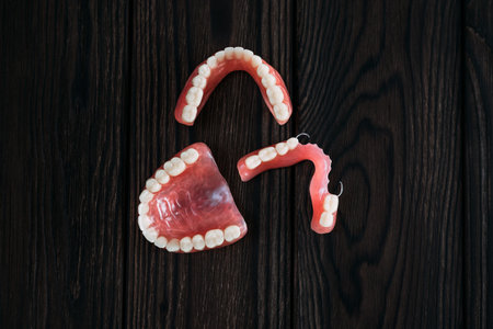 Dentures on a dark background. Close-up of dentures. Dentistry is conceptual photography. Prosthetic dentistry. False teeth. Prosthetics. Close-up of plastic dentures. Teeth on a wooden backgroundの写真素材