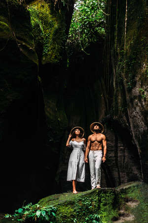 Traveling couple in a cave. A couple in love in a cave on the island of Bali. The couple travels to the island of Bali in Indonesia. Vacation on a tropical island. Copy spaceの写真素材