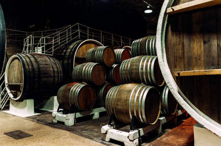 Old barrels in the wine cellar. Wine cellar with old oak barrels, production of fortified dry or semi-sweet wine. The wine barrels are stored in the old cellar of the winery. Brewery, wineryの写真素材