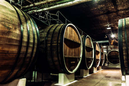 Old barrels in the wine cellar. Wine cellar with old oak barrels, production of fortified dry or semi-sweet wine. The wine barrels are stored in the old cellar of the winery. Brewery, wineryの写真素材