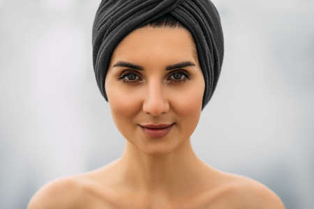 Portrait of a beautiful girl with a turban on her head. Pretty close-up face of a fashionable woman. Fashion oriental style woman. Portrait of white-skinned girl in a turban.の写真素材