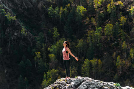 Healthy lifestyle and relaxation concept. Yoga in the fresh air. Happy woman doing yoga exercises. Meditation and relaxation. A woman practicing yoga in the mountains. A woman meditates in natureの写真素材