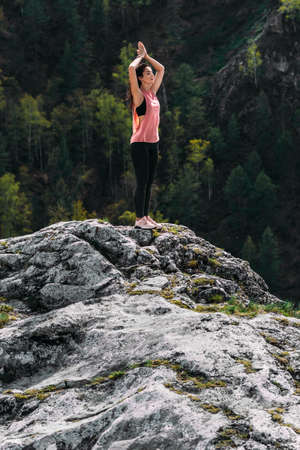 A slender woman does yoga exercises against an incredible backdrop of nature. The girl does yoga in the fresh air. Healthy and yoga concept. Meditation and Relax. Healthy Lifestyle. Copy spaceの写真素材