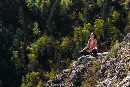 Attractive woman doing yoga. Healthy lifestyle. Woman doing yoga in the mountains. Girl doing yoga at sunrise. Woman meditates in nature. Meditation in the mountains. Copy spaceの写真素材