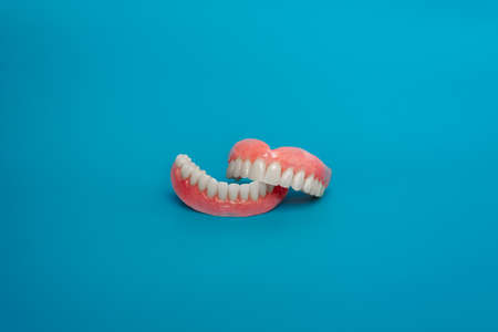Full removable plastic denture of the jaws. Set of dentures on a blue background. Two acrylic...