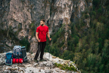 A traveler with a backpack in the mountains. A man with a backpack. The concept of a hiking lifestyle. Hiking in the mountains in the summer with a backpack. Travel, traveler, backpack. Copy spaceの写真素材