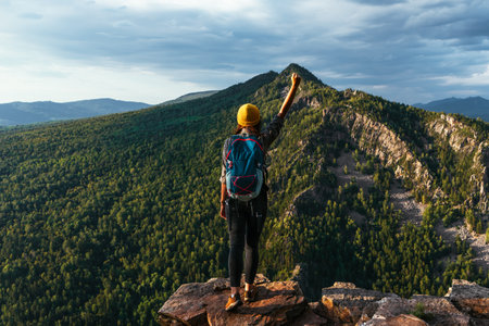 The traveler is happy to climb the mountain. A girl meets the sunset in the mountains. Mountain sports. The man on the top of the mountain. Mountain tourism. A trip to the mountains. Copy spaceの写真素材