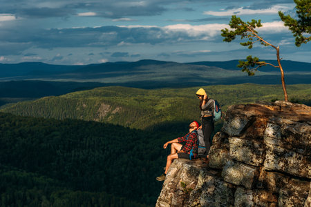 A couple meets the sunset in the mountains. A man and a woman in the mountains. Wedding travel. Honeymoon trip. A couple of travelers in love. People greet the dawn. Lovers travel. Copy spaceの写真素材