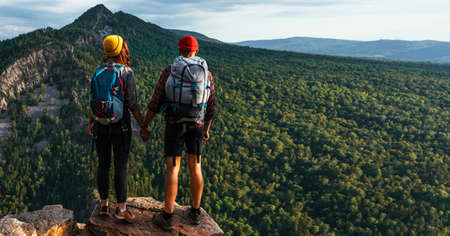 A traveling couple in the mountains. A man and a woman on the background of a mountain, a panorama. Climbing the mountain. Hiking in the mountains. Active recreation in the national park. Copy spaceの写真素材