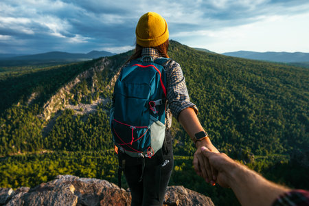 Portrait of a woman holding her man's hand while walking along a mountain range. The couple is enjoying a walk in nature. A guy holds his girlfriend's hand in the mountains. A trip to the mountainsの写真素材