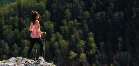 The traveler is happy to climb the mountain. Hiking in the mountains. Mountain sports. The man on the top of the mountain. Mountain tourism. A trip to the mountains. Copy spaceの写真素材