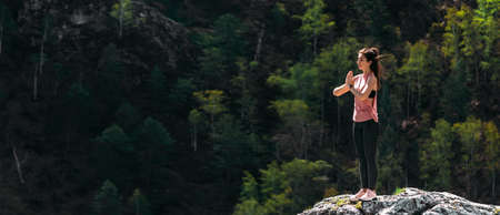 An attractive and healthy young woman does yoga in the mountains at dawn. Yoga in the fresh air. Happy woman doing yoga exercises. Meditation in nature. A woman practicing yoga in the mountainsの写真素材