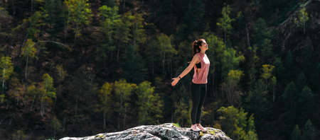 An attractive and healthy young woman does yoga in the mountains at dawn. Yoga in the fresh air. Happy woman doing yoga exercises. Meditation in nature. A woman practicing yoga in the mountainsの写真素材