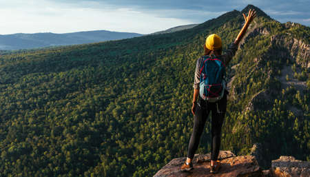 The traveler is happy to climb the mountain, panorama. A girl meets the sunset in the mountains. Mountain sports. The man on the top of the mountain. Mountain tourism. A trip to the mountainsの写真素材