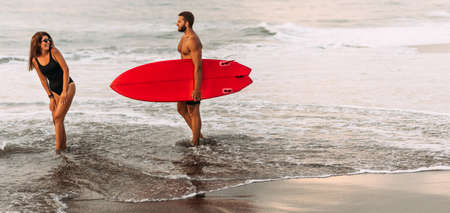 A couple in love on vacation on the ocean, panorama. Surfing on the shore of the paradise island of Sri Lanka. A married couple is resting on the sea. A happy couple by the sea. Holidays in Sri Lankaの写真素材
