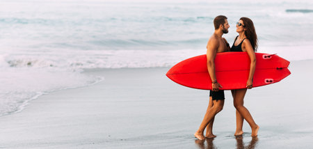 Surfing on the shore of the paradise island. A couple in love on vacation on the ocean. A married couple is resting on the sea. A happy couple by the sea. Vacation in Bali, Indonesia. Copy spaceの写真素材