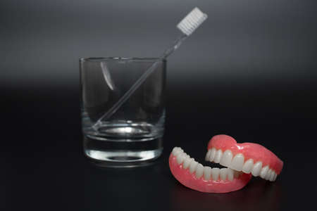 Full removable plastic denture of the jaws. A set of dentures on a black background. Two acrylic dentures. Upper and lower jaws with fake teeth. Dentures or false teeth, close-up. Copy spaceの写真素材