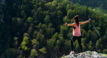 The traveler is happy to climb the mountain, panorama. A girl meets the sunset in the mountains. Mountain sports. The man on the top of the mountain. Mountain tourism. A trip to the mountainsの写真素材