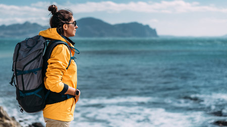 A tourist with a backpack on the background of a seascape, panorama. Portrait of a woman in tourist gear on the background of the sea. The concept of travel and an active lifestyle. Copy spaceの写真素材