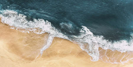 Sea coast with light sand and blue sea, panorama. Sandy beach with sea waves, panoramic view. A lonely sandy beach with waves. The sea coast from a bird's-eye view. Shoreline from a height. Copy spaceの写真素材