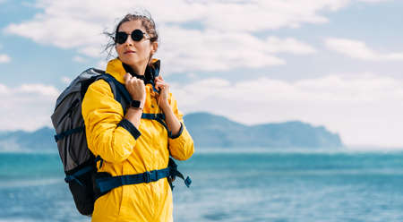 Portrait of a female traveler on the background of the sea. The concept of adventure, travel and hiking. A female tourist enjoys a beautiful landscape during a hike. Portrait of a tourist by the seaの写真素材