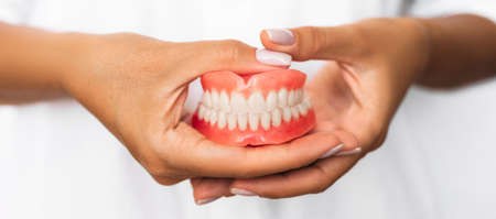 Dental prosthesis in the hands of the doctor close-up. Dentist holding ceramic dental bridge. Front...