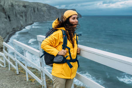 Portrait of a female traveler on the background of the sea. The concept of adventure, travel and hiking. A female tourist enjoys a beautiful landscape during a hike. Portrait of a tourist by the seaの写真素材