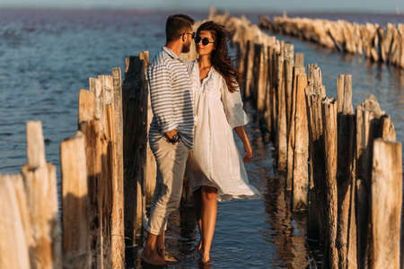 A couple in love on the seashore. A happy couple on a honeymoon by the sea. A beautiful couple on the coast. The honeymoon. Wedding trip. Copy spaceの写真素材