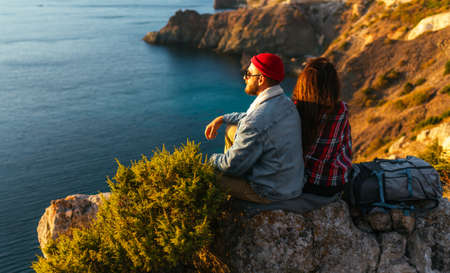 A couple in love at sunset by the sea. The honeymoon. Wedding trip. A man and a woman by the sea. A man and a woman on the coast enjoy the sunset. A stylish couple admires the sea sunset. Copy spaceの写真素材