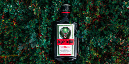Chelyabinsk, Russia - July 30, 2021: Jagermeister. A bottle of Jagermeister on the lingonberry bushes. Bottle of Jagermeister, German digestif made with 56 herbs. Jagermeister herb liqueur bottle.のeditorial素材