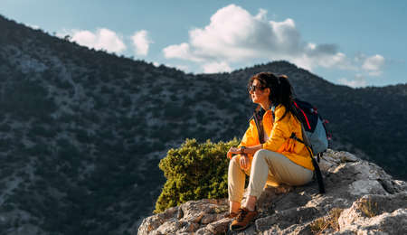 Portrait of a female traveler in the mountains. Adventure, travel and hiking concept. A happy woman...