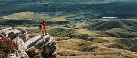 A traveling couple in the mountains. A man and a woman on the background of a mountain, a panorama. Climbing the mountain. Hiking in the mountains. Active recreation in the national park. copy spaceの写真素材