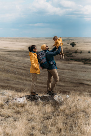A traveling family. Traveling with a child. A traveling couple in hiking gear. Hiking with a backpack. The happy family went camping. Family in camping gear against the background of natureの写真素材