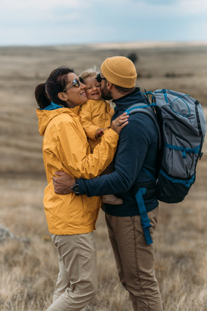 A traveling family. Traveling with a child. A traveling couple in hiking gear. Hiking with a backpack. The happy family went camping. Family in camping gear against the background of natureの写真素材