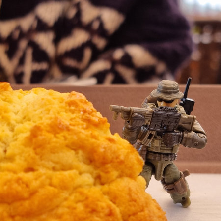 A closeup shot of a toy soldier holding a large piece of bread.