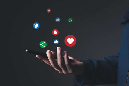 A man right hand side catching the mobile chat with his friend, online internet social media with vector icon such like, love and share, technology and internet conceptの写真素材