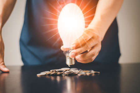 A man with coin money saving and investment growth business, success, computer graphic orange light, banking and related conceptの写真素材