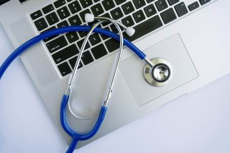 A laptop with a stethoscope lying on top of it from top view perspective.の写真素材