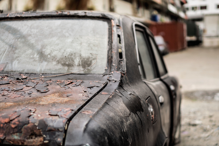 Old abandoned rusty car at the back alleyの写真素材