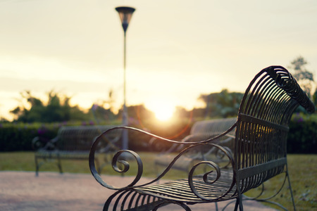 Black iron bench in the city park during sunsetの写真素材