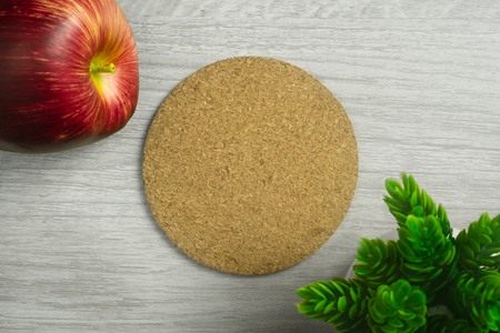 Cork board on light wood background with apple and potted plant.の写真素材