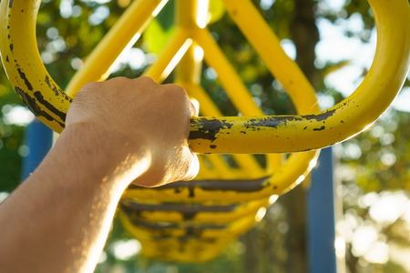 Hand holding metal triangle hanging bar at recreational park.の写真素材