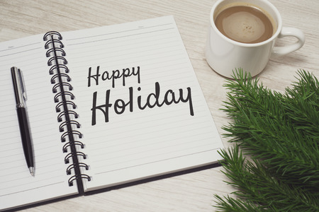 Happy Holiday written on notebook placed on top of wood desk. Festival and celebration concept.の写真素材