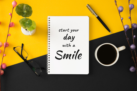 Notebook with motivational and inspirational wisdom quote on yellow and black background. Start your day with a smile.の写真素材