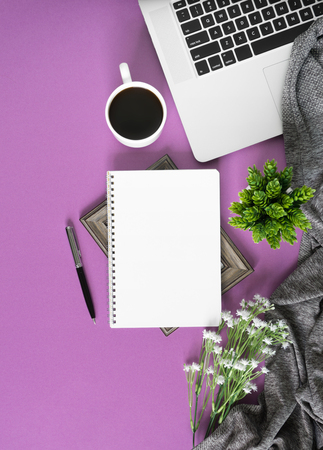 Home work space with notebook, laptop and coffee on pastel violet background. Home office flat lay top view.の写真素材